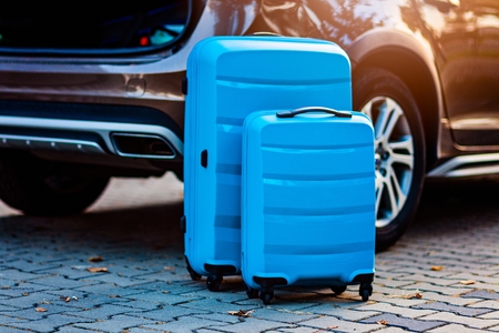 Two blue plastic suitcases near the car. Preparation for tripの写真素材