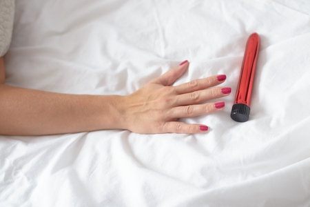 Woman in bed reaching for dildo vibrator. Woman and sex toyの写真素材