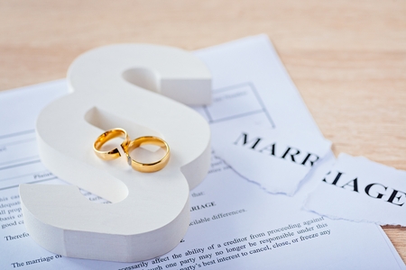 Two broken wedding rings on wooden paragraph. Divorce, separation and family law conceptの写真素材