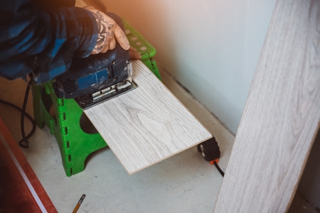 Worker cutting with electric jigsaw laminate floor panel. Home improvement and renovation conceptの写真素材