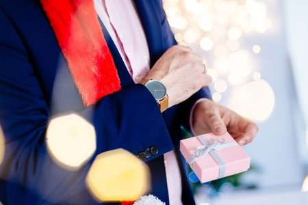 Handsome man in red santa claus christmas hat holding present box. Christmas giftの写真素材