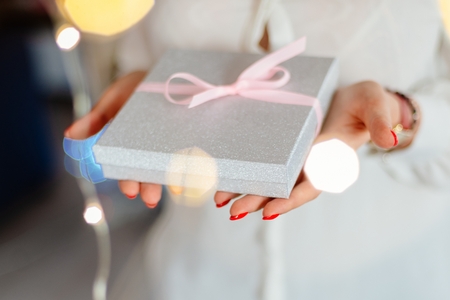 Young woman giving box with ribbon surprise gift. Christmas present giftの写真素材