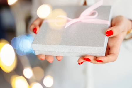 Young woman giving box with ribbon surprise gift. Christmas present giftの写真素材