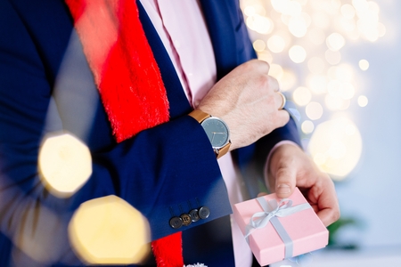 Handsome man in red santa claus christmas hat holding present box. Christmas giftの写真素材