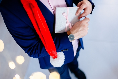 Handsome man in red santa claus christmas hat holding present box. Christmas giftの写真素材