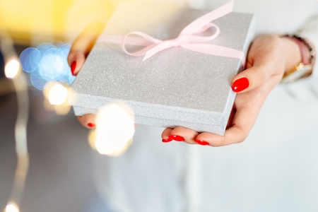 Young woman giving box with ribbon surprise gift. Christmas present giftの写真素材