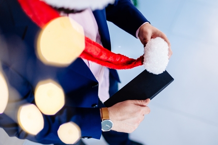 Handsome man in red santa claus christmas hat holding present box. Christmas giftの写真素材