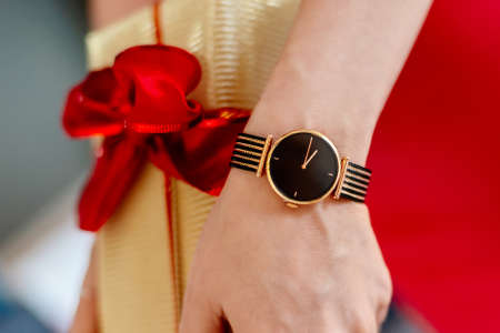 Woman in red dress giving Christmas gift in gold box with red ribbon. Christmas surprise. Merry Christmas!の写真素材