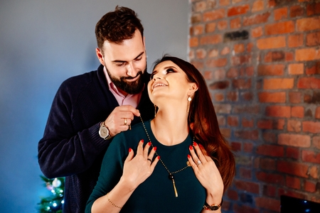 Man helps his wife to wear jewelry necklace. Puts necklace on her neckの写真素材