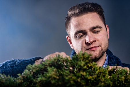 Studio shot of young man pruning japanese bonsai tree. Hobby and passion concept