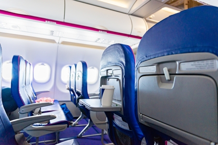 Seats and cup of tea in passenger airplane. Passenger plane interior, economy class