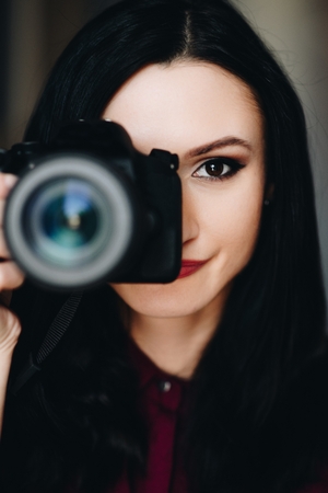 Portrait of young woman taking photo with dslr camera. Woman photographerの写真素材