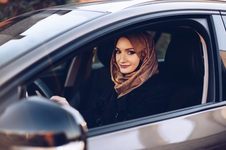 Young arabic woman in hijab driving a car