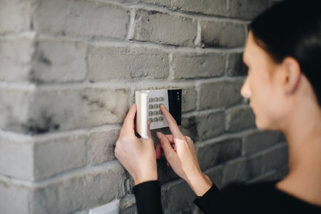 Young woman entering security pin on home alarm keypad. Home security systemの写真素材