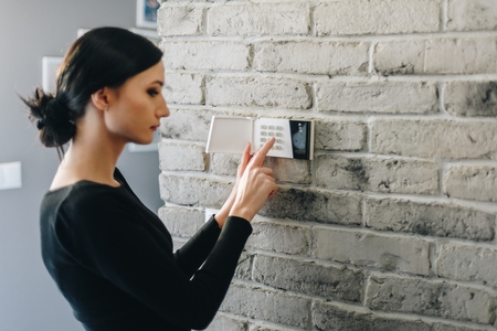 Young woman entering security pin on home alarm keypad. Home security systemの写真素材