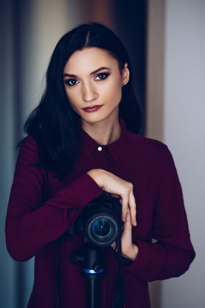 Young woman with dslr camera on tripod. Woman photographerの写真素材