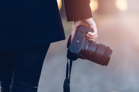 Close up on dslr photo camera holded by woman photographer outdoors