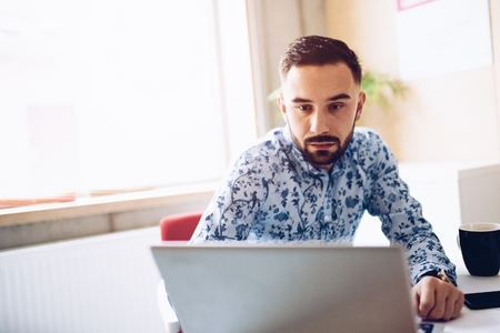 Caucasian concentrated businessman working on laptop computer in his office. Man working in officeの写真素材
