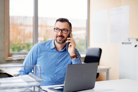 40 years old middle aged handsome man working on laptop computer in office. Man working in officeの写真素材