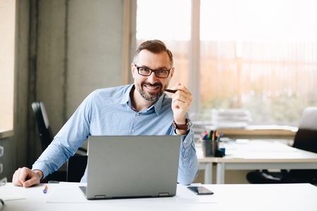 40 years old middle aged handsome man working on laptop computer in office. Man working in officeの写真素材