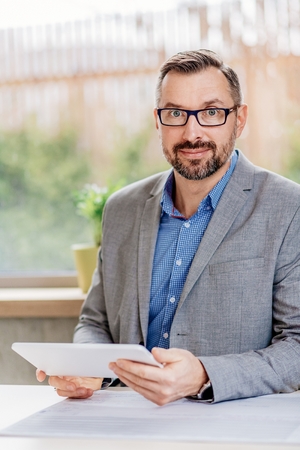 40 years old handsome businessman working on tablet computer in office. Man working in officeの写真素材