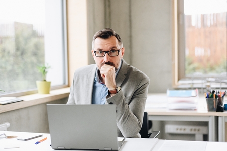 Middle aged handsome businessman working on laptop computer in office. Man working in officeの写真素材