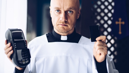 Catholic priest holding credit card reader. Money and religionの写真素材