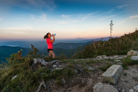 Woman cross country runner drinking water in mountains at summer. Woman running. Silesian Beskid, Szczyrkの写真素材