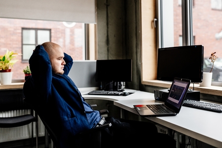 Relaxed man working in office on laptop computer. Young businessman in officeの写真素材