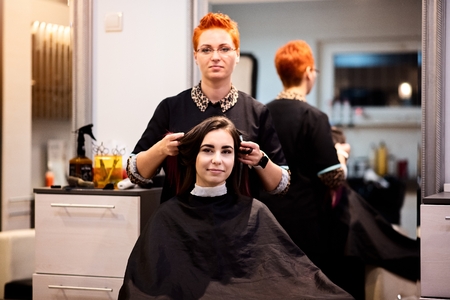 Woman hairdresser showing new haircut to her customer. Female in hairdresser salonの写真素材