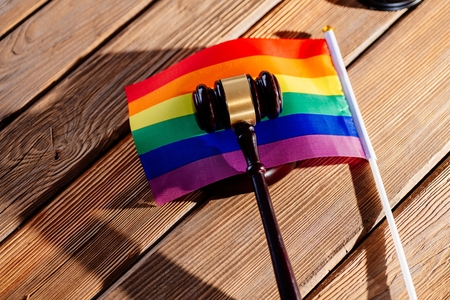 Judge wooden mallet - symbol of law and justice with lgbt rainbow colours flag. Lgbt rights and law