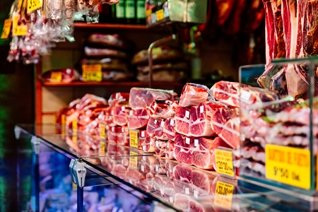 Traditional smoked Spanish ham on display in butcher stand on marketの写真素材