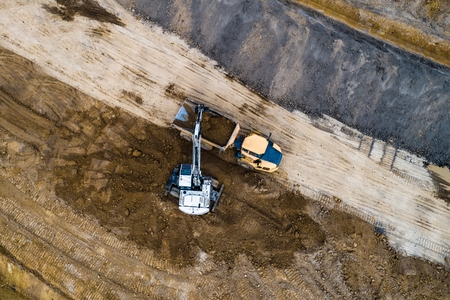 Excavator loader loading ground on truck. Road construction