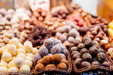 Sweet balls in white chocolate, coconut and dark chocolate on display in confectionary candy storeの写真素材