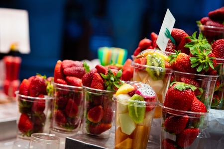 Red fresh strawberries, pitaya and other juicy fruits in plastic cup for take away. Healthy lunchの写真素材