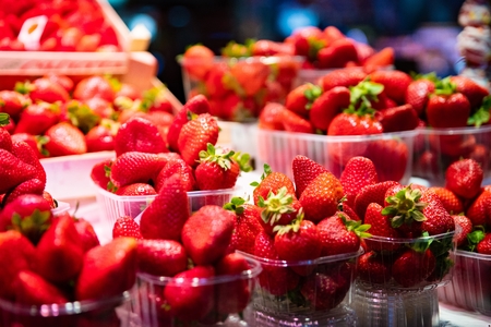 Plastic baskets with fresh red strawberries for sale on market stallの写真素材