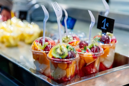 Plastic cups with delicious fruits for sale. Kiwi, pineapple and other juicy fruits in plastic cup. Takeaway fruitsの写真素材