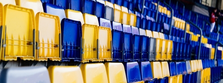 Yellow and blue plastic empty stadium seats. Football stadium