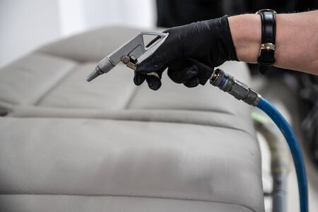 Woman worker of car wash impregnating leather car seatの写真素材