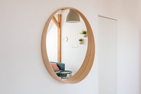 Round mirror on the living room wall with reflection of living roomの写真素材