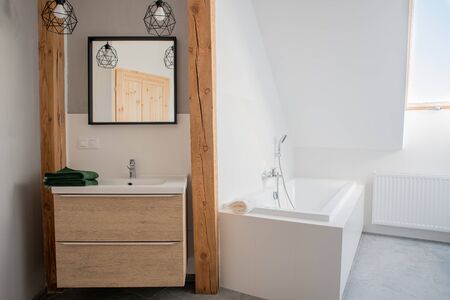 loft bathroom with mirror and bathtub. White wallsの写真素材