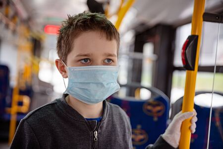 Child in protective mask travelling by public bus