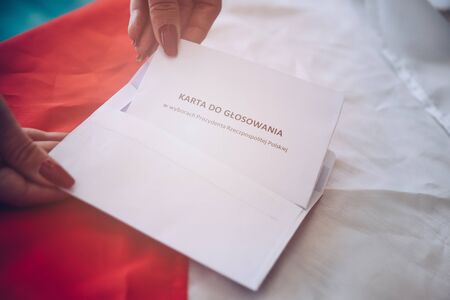 Woman putting correspondence postal ballot paper to envelope. Ballot paper in correspondence president elections in Republic of Polandの写真素材