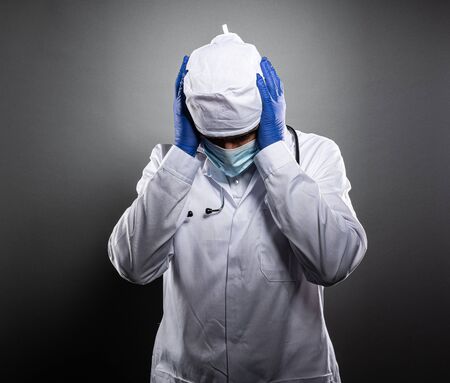 Overworked tired doctor in white uniform and medical mask.の写真素材