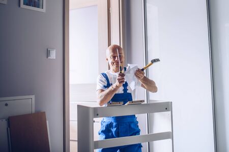 Nervous carpenter assembling furniture and tearing instruction manualの写真素材