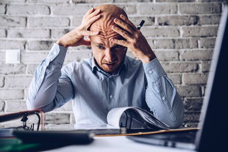 Finacial problems and crisis. Stressed depressed man reading bills and loan contract. Finacial...
