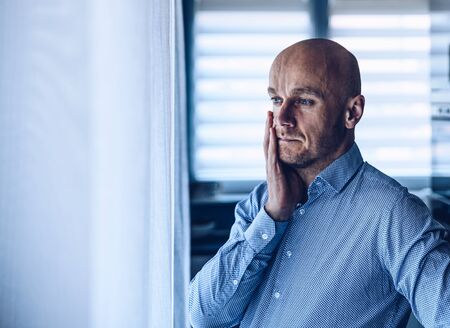 Worried depressed man looking throught the window.の写真素材