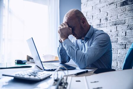 Worried confused man in shirt working on laptop computerの写真素材