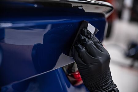 Man worker of car detailing studio applying ceramic coating on car paint with sponge applicator.の写真素材