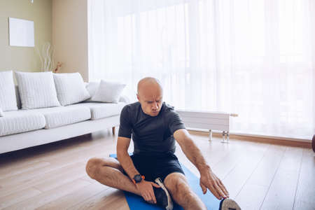 Home workout. Man doing hamstring stretching at home.の写真素材